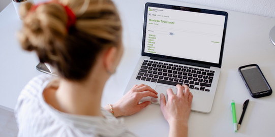 Foto einer Frau, die auf einen Laptop blickt.